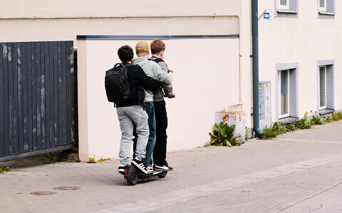 Young people riding an electric scooter.