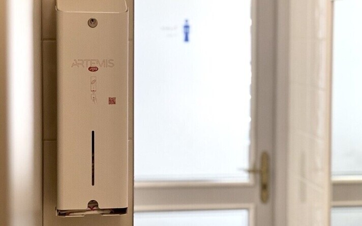 A menstrual pad dispenser in a public bathroom.